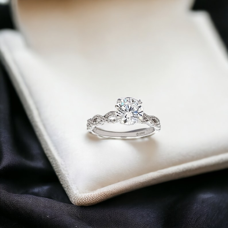 May include: A silver engagement ring with a large, round, clear diamond set in a braided band.