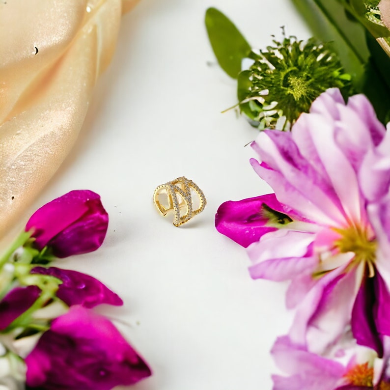 May include: Gold ear cuff with a delicate design featuring multiple rows of sparkling clear cubic zirconia stones.