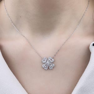 May include: A silver chain necklace with a four-leaf clover pendant set with clear cubic zirconia stones.
