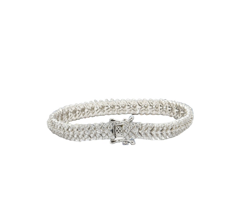 May include: A silver tennis bracelet with a double row of pave set diamonds.