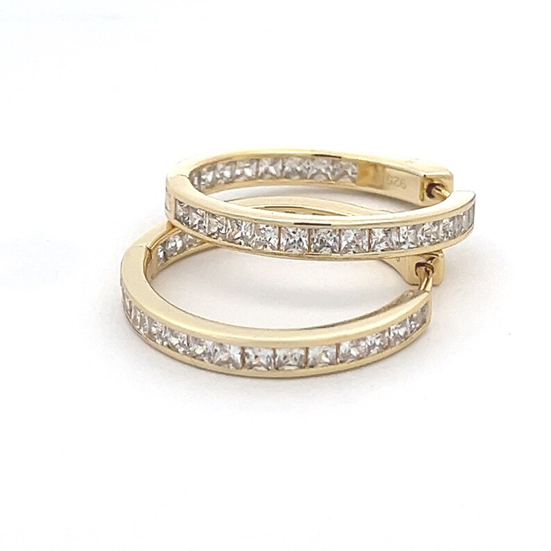 May include: A pair of gold hoop earrings with a row of clear square-shaped stones around the edge.
