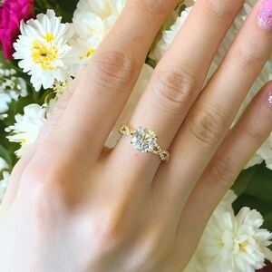 May include: A gold engagement ring with a large, round, clear diamond center stone. The ring has a delicate, twisted band with smaller diamonds set along the sides.