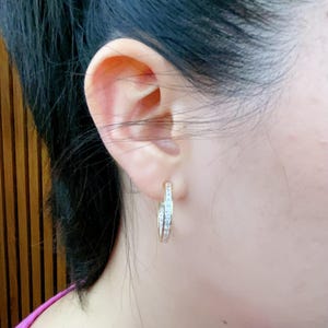 May include: A pair of gold hoop earrings with a row of small clear stones around the edge.