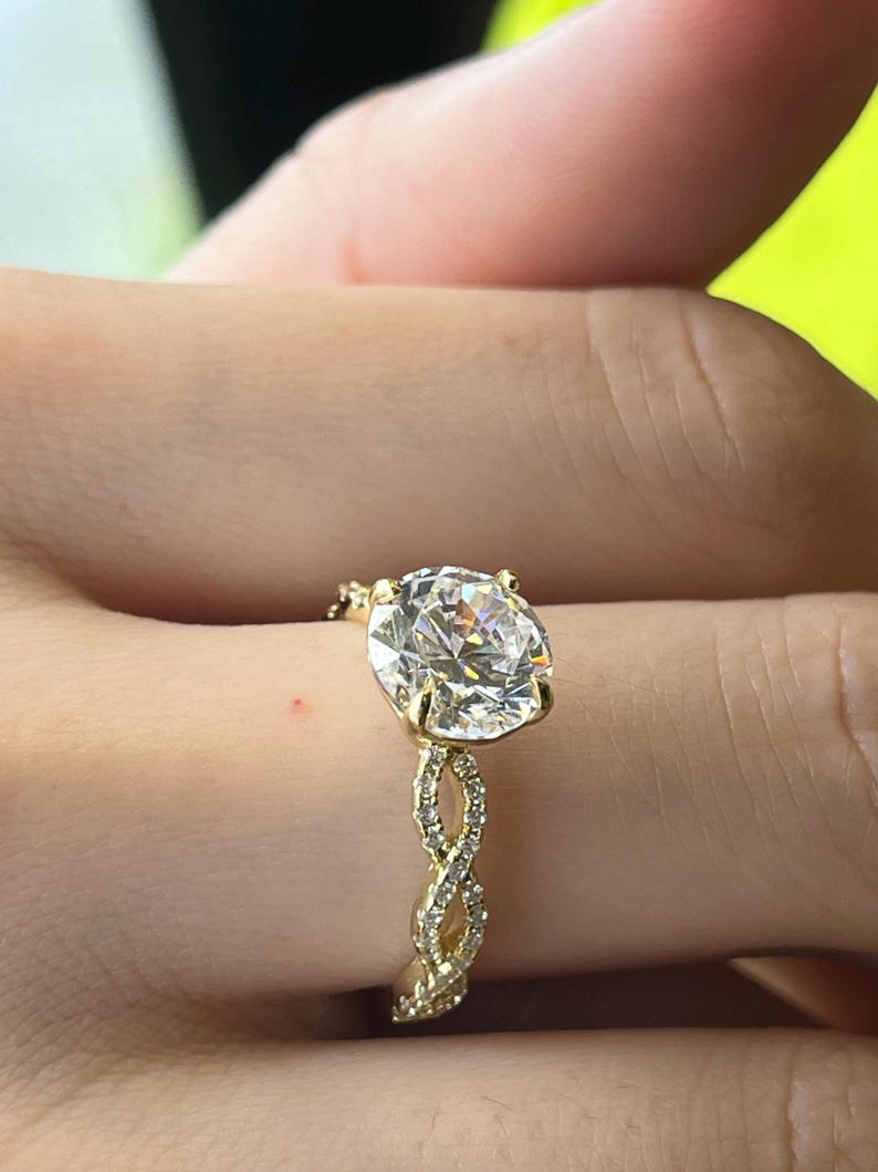 May include: A gold engagement ring with a large round diamond center stone and a braided band of smaller diamonds.