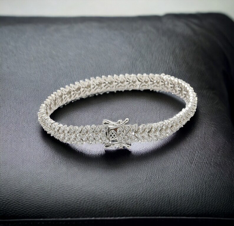 May include: A silver tennis bracelet with a row of small, clear cubic zirconia stones.