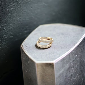 May include: A pair of gold hoop earrings with a row of small, clear cubic zirconia stones set in the band.