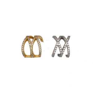 May include: Two ear cuffs, one gold and one silver, with a criss-cross design and clear cubic zirconia stones.