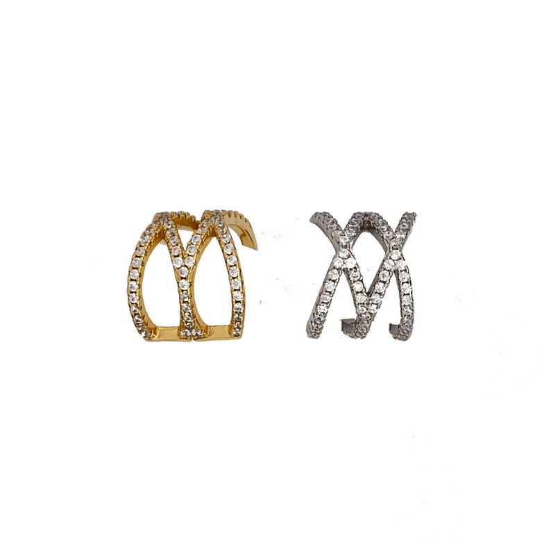 May include: Two ear cuffs, one gold and one silver, with a criss-cross design and clear cubic zirconia stones.