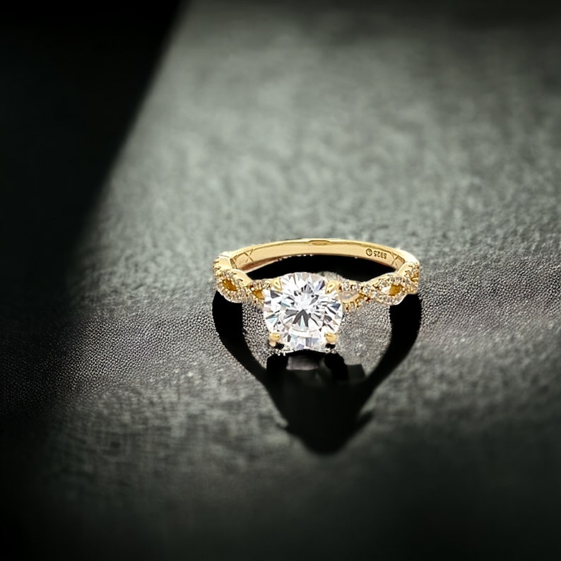 May include: A gold engagement ring with a large, round, clear diamond center stone. The band is twisted and features smaller diamonds.