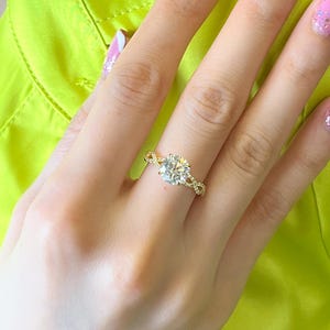 May include: A gold ring with a large, round, clear diamond center stone. The ring has a delicate, twisted band.