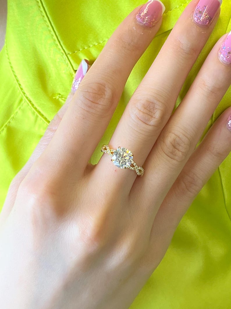 May include: A gold ring with a large, round, clear diamond center stone. The ring has a delicate, twisted band.