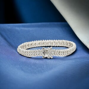 May include: A silver tennis bracelet with a row of small, clear cubic zirconia stones.