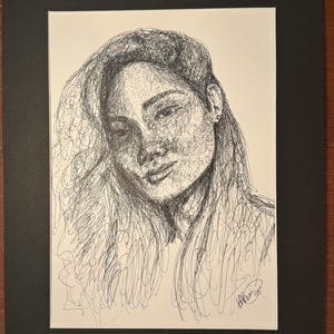 Peut inclure: Portrait au stylo et encre d'une personne aux longs cheveux, créé avec une série de lignes griffonnées. L'œuvre est montée sur un passe-partout blanc et encadrée d'un bord noir. Signé dans le coin inférieur droit.