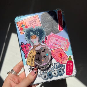 May include: A clear phone case decorated with stickers. Stickers include text that says "Touch Her and Die book club", "I Vow", "We Vow", "Try Crime", "Fourth Wing", "In my Spicy Book", and "Spicy Lover".