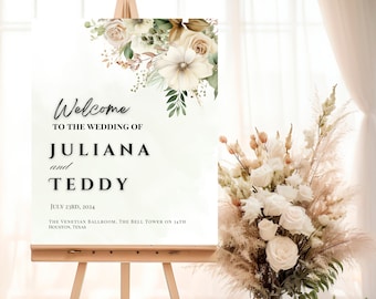 May include: A wedding welcome sign with a floral design in shades of white, cream, and green. The sign reads "Welcome to the wedding of Juliana and Teddy, July 23rd, 2024, The Venetian Ballroom, The Bell Tower on 34th, Houston, Texas."