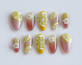 Puede incluir: Conjunto de diez uñas postizas con un diseño de rodaja de limón y flor. Las uñas son de color rosa claro con una rodaja de limón amarilla y una flor blanca en cada uña.