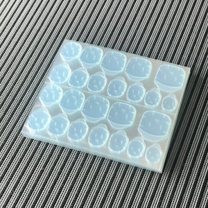 May include: A sheet of clear, plastic adhesive dots. The dots are arranged in rows and columns, with each dot having a slightly raised centre.