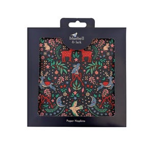 May include: A pack of paper napkins featuring a dark background with a forest-themed pattern. The design includes deer, rabbits, birds, and crescent moons in red, green, and blue. The package has the text "bluebell & lark" and "Paper Napkins".