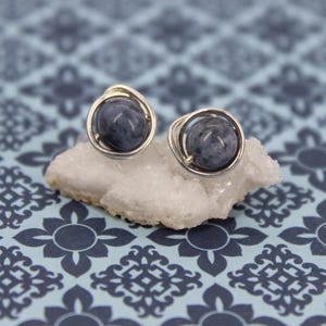 May include: A pair of silver wire wrapped earrings with blue gemstone cabochons.