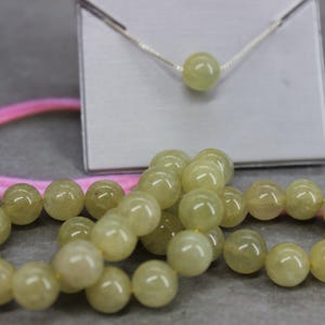 May include: Two bracelets made of light green beads, one with a silver chain and a single light green bead pendant.