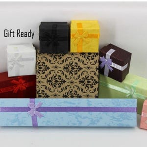 May include: A collection of various square and rectangular gift boxes in colors including black, yellow, white, red, dark brown, light green, pink, and magenta, with a long light blue box in front. The text Gift Ready is visible.
