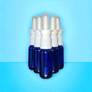 May include: Six blue glass bottles with white spray tops. The bottles are arranged in a pyramid shape.