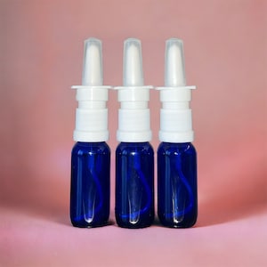 May include: Three blue glass bottles with white spray tops. The bottles are filled with a clear liquid.