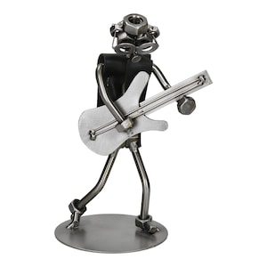 May include: A metal sculpture of a musician playing a guitar. The figure is constructed from nuts, bolts, and metal rods, with a black leather vest. The guitar is silver and the figure stands on a circular base.