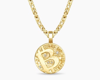 Puede incluir: Un collar con colgante de Bitcoin dorado. El colgante presenta el símbolo de Bitcoin con gemas incrustadas y la inscripción "VIRES IN NUMERIS". La cadena tiene un diseño texturizado y enlazado.