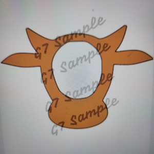 Puede incluir: Un recorte de cabeza de vaca marrón con un círculo en el medio. El recorte es perfecto para un proyecto de manualidades o para usarlo como decoración.