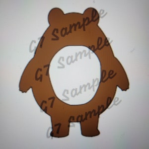 Puede incluir: Un cortador de galletas con forma de oso marrón con un agujero en el medio. El cortador de galletas está de pie sobre una superficie blanca.