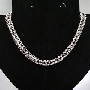 May include: A silver chain necklace with a woven pattern.