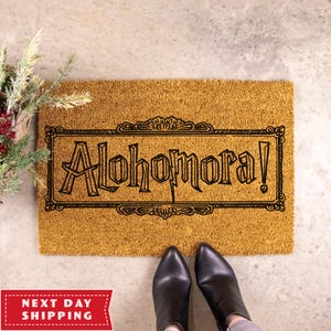 May include: A brown coir doormat with the text "Alohomora!" in a black, decorative font.