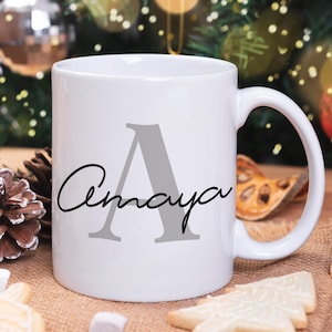 May include: White ceramic mug with a gray letter A and the name Amaya written in black cursive script.