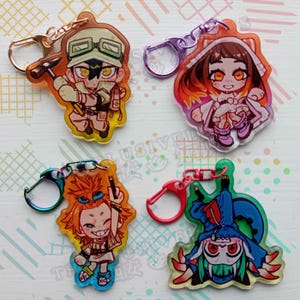Könnte beinhalten: Vier farbenfrohe Acryl-Schlüsselanhänger mit Anime-Charakteren. Jeder Schlüsselanhänger hat ein anderes Charakterdesign mit leuchtenden Farben und angebrachten Metallverschlüssen. Die Schlüsselanhänger sind im Cartoon-Stil gestaltet.