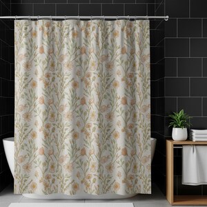 May include: A floral shower curtain featuring a repeating pattern of peach and yellow flowers, green leaves, and butterflies on a cream background. The curtain is hanging in front of a white bathtub, with a black tiled wall in the background.