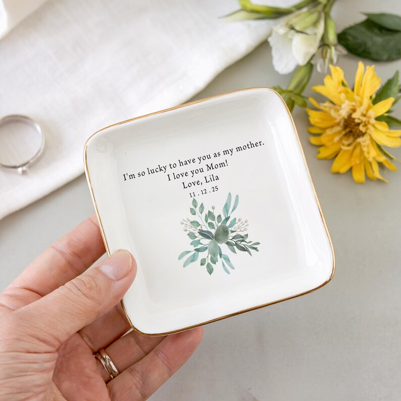 Puede incluir: Plato de cer&aacute;mica blanca para joyas con borde dorado. El plato tiene un dise&ntilde;o floral y el texto "I'm so lucky to have you as my mother. I love you Mom! Love, Lila 11.12.25"