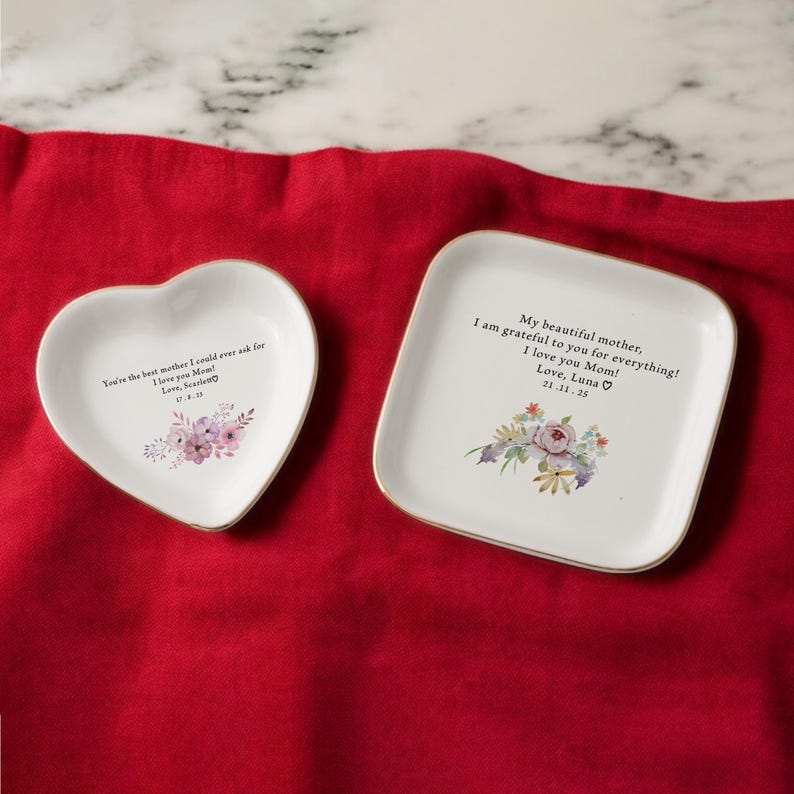 Puede incluir: Dos platos de cer&aacute;mica blanca para joyas con ribete dorado. Un plato tiene forma de coraz&oacute;n y el otro es cuadrado. Ambos platos presentan dise&ntilde;os florales y mensajes personalizados. El plato en forma de coraz&oacute;n dice "You're the best mother I could ever ask for. I love you Mom! Love, Scarlen". El plato cuadrado dice "My beautiful mother, I am grateful to you for everything! I love you Mom! Love, Luna 21.11.25".