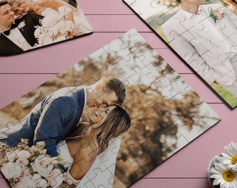 May include: A wedding couple poses for a photo in a wooded area. The groom is wearing a dark blue suit jacket and the bride is wearing a white wedding dress. The couple is surrounded by trees and foliage.