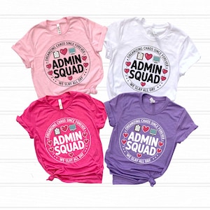 Può includere: Quattro magliette a maniche corte in rosa chiaro, bianco, rosa acceso e lavanda. Ogni maglietta presenta una grafica circolare con il testo "ADMIN SQUAD", "ORGANIZING CHAOS SINCE FOREVER" e "WE SLAY ALL DAY", accompagnata da icone di cartellina, cuore e computer.