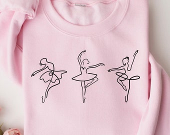 May include: A pink sweatshirt with a black line drawing of three ballerinas on the front.