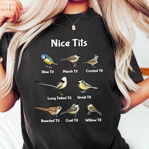 May include: Black t-shirt with the text "Nice Tits" and illustrations of different types of birds with their names below each image: Blue Tit, Marsh Tit, Crested Tit, Long Tailed Tit, Great Tit, Bearded Tit, Coal Tit, Willow Tit.