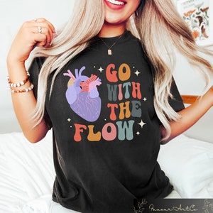 May include: Black t-shirt with a colorful graphic of a heart and the text "GO WITH THE FLOW" in a retro font.
