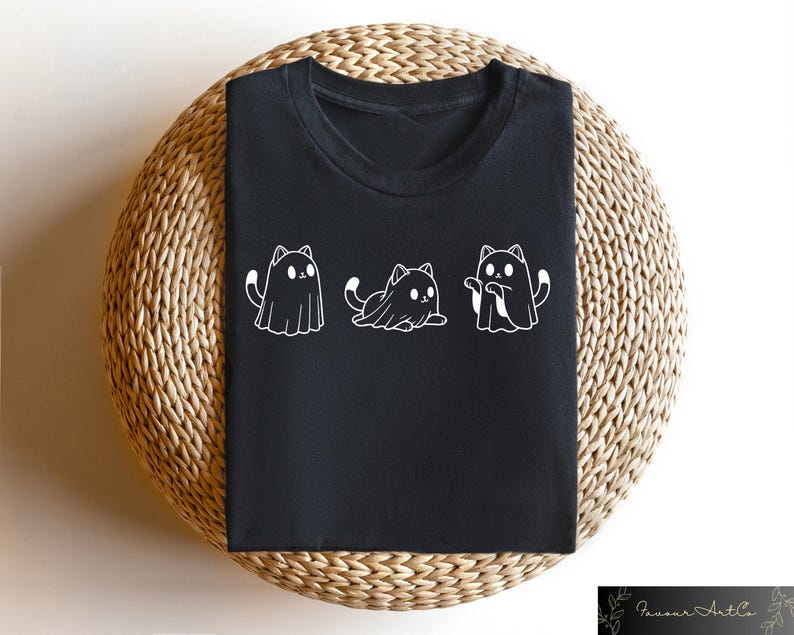 Pu&ograve; includere: Maglietta nera con una grafica bianca di tre gatti vestiti da fantasmi. I gatti sono in fila, con il gatto al centro seduto e i gatti ai lati in piedi.