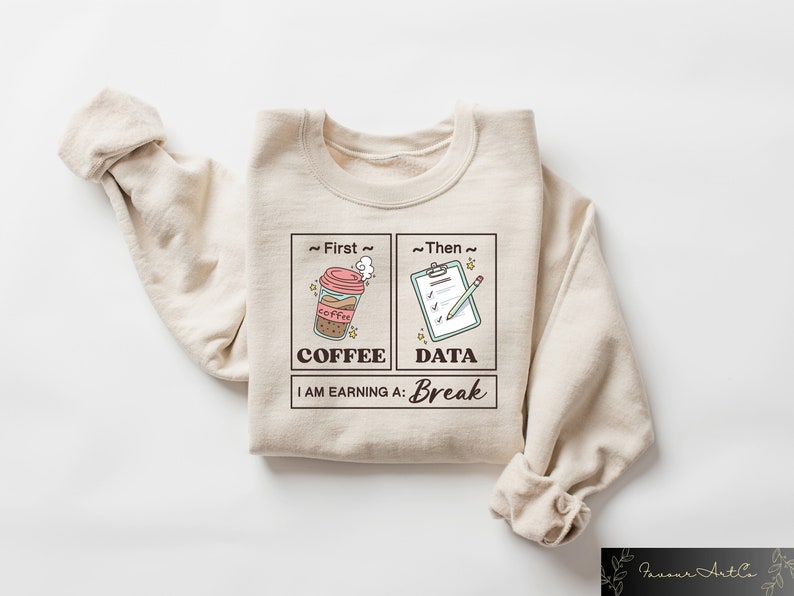 May include: Beige sweatshirt with a graphic design of a coffee cup and a checklist. The text reads "~First~ Coffee ~Then~ Data I AM EARNING A: Break"