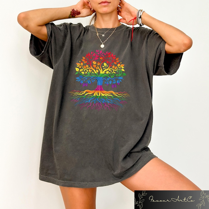May include: Dark gray t-shirt featuring a colorful tree design in rainbow colors. The tree has a trunk, branches, leaves, and roots, all in a vibrant spectrum. The shirt is a comfortable, oversized fit.