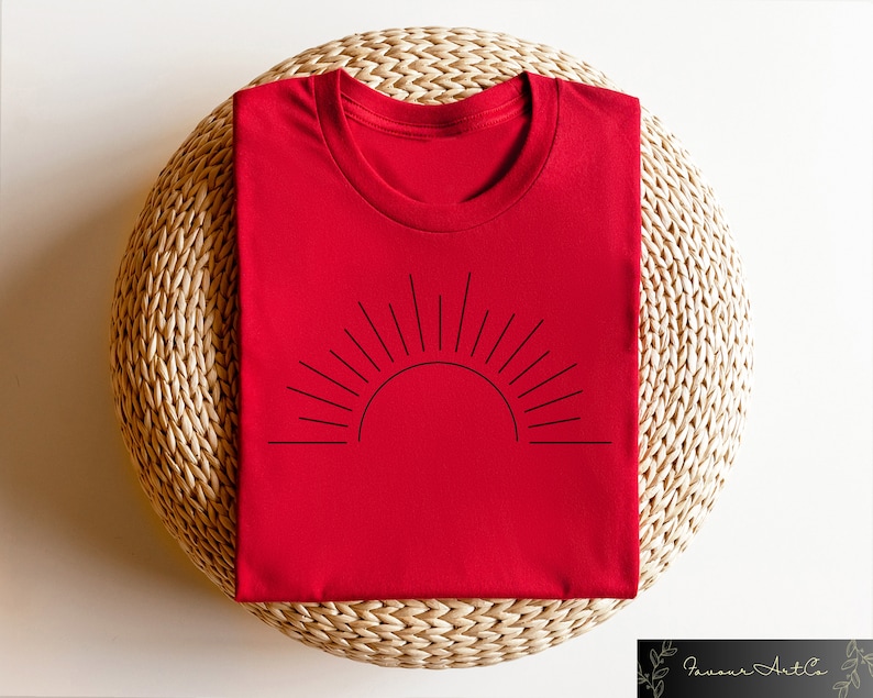 May include: Red t-shirt with a black line drawing of a sun with rays on the front.