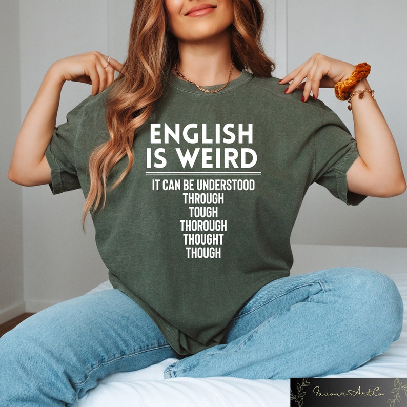 May include: A green t-shirt with the text "English is Weird" and the words "It can be understood through tough thorough thought though" printed in white.