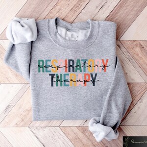 May include: Gray sweatshirt with the text "RESPIRATORY THERAPY" in colorful letters.