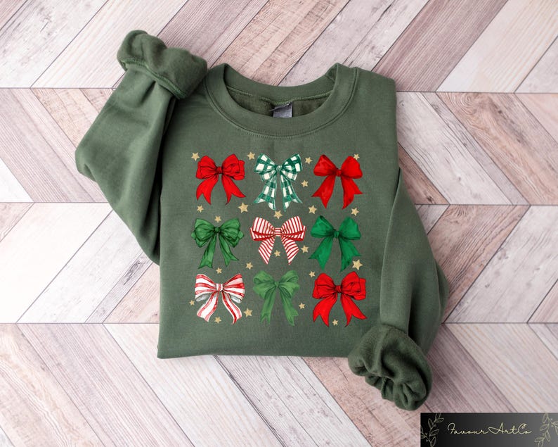 May include: A green sweatshirt with a Christmas-themed design featuring multiple red and green bows with gold accents.